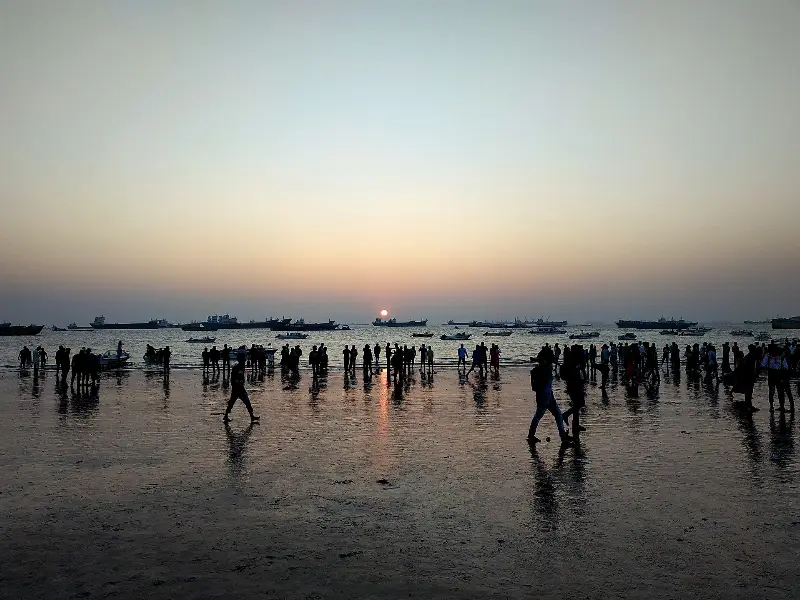 সন্ধ্যায় পতেঙ্গার ভেজা বালিতে দর্শনার্থী, দিগন্তে অপেক্ষমাণ জাহাজ